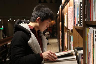 Un jeune chinois qui lit un livre dans une librairire