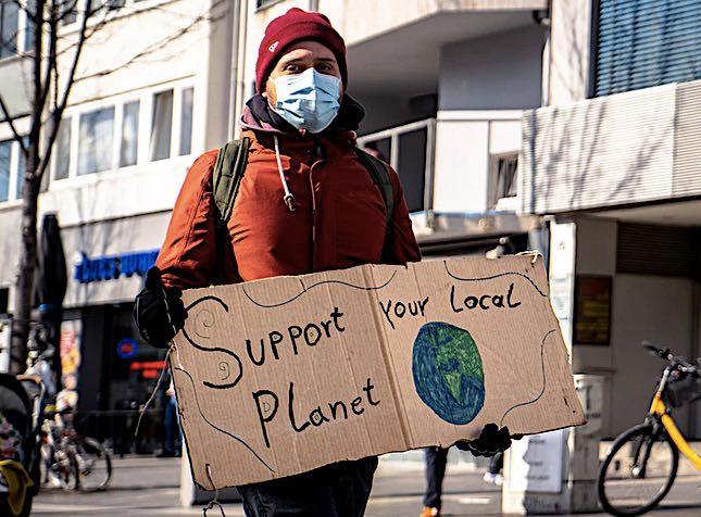 Une écologiste avec une pancarte support your local planet