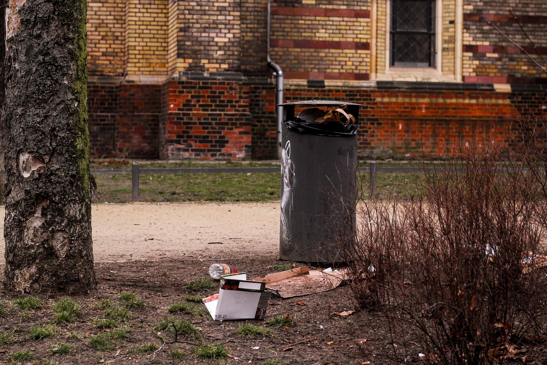 Une poubelle dans un parc à Berlin avec des déchets par terre 