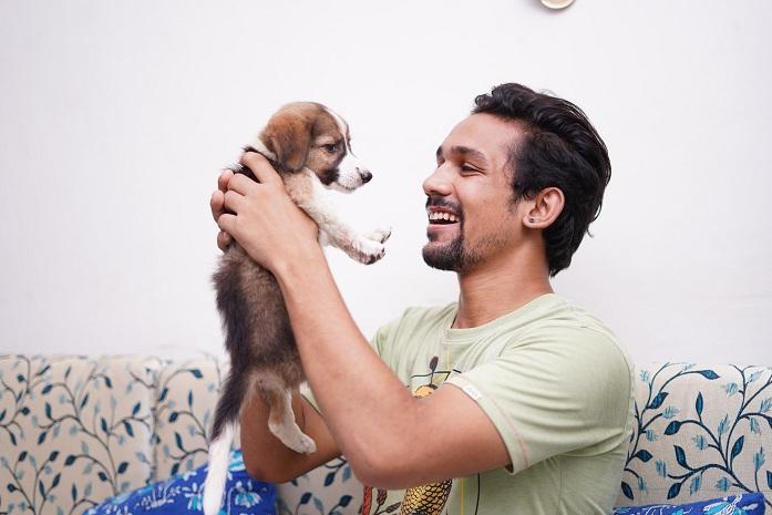 un homme souriant prend dans ses bras un petit chiot 