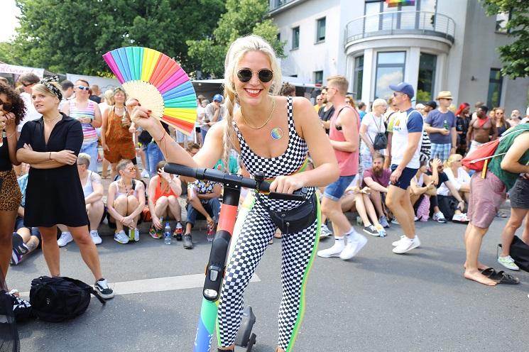 Une jeune femme sur son e-scooter, elle tient un éventail multicolore