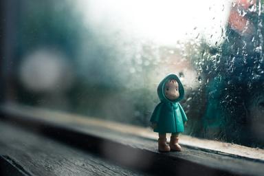 Une figurine sous un anorak sous un ciel pluvieux 