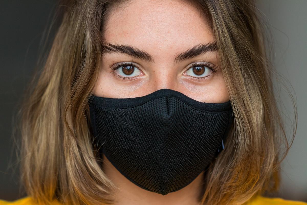 une jeune femme au regard vide porte un masque noir 