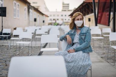 Une femme masquée avec des chaises vides 