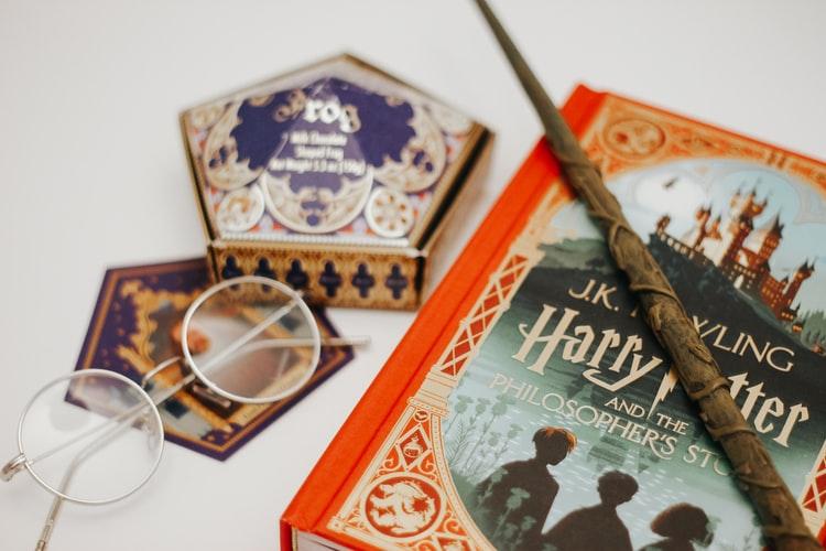 Les livres de la saga Harry Potter et une baguette trônent sur une table 