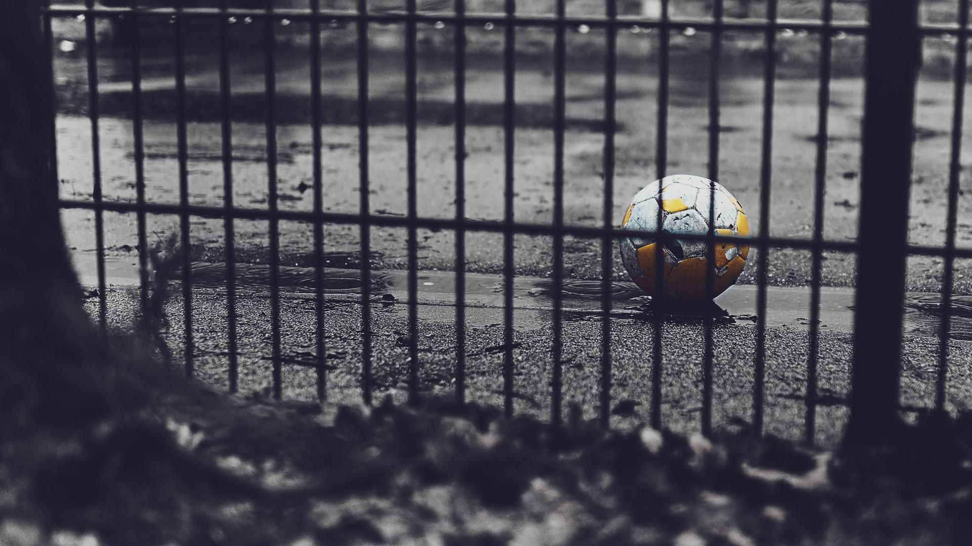 Un ballon de football derrière une grille