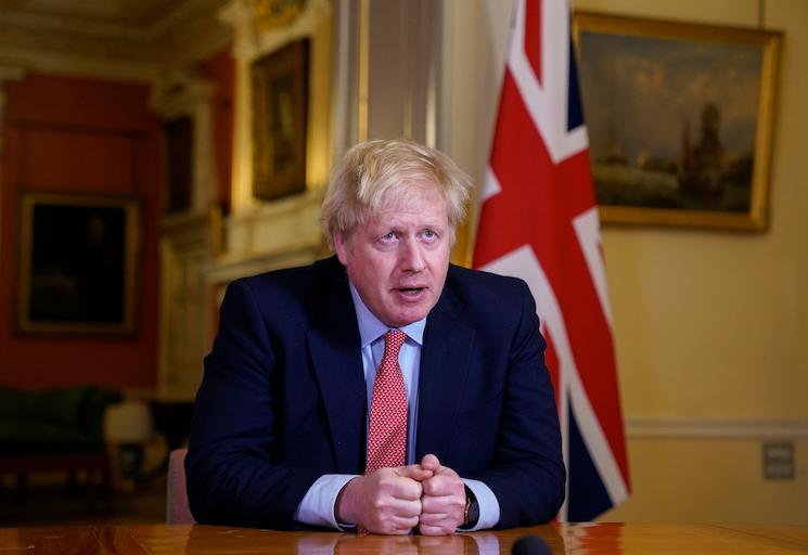 Le Premier ministre britannique Boris Johnson à son bureau avec un drapeau anglais en fond