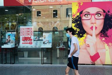 une personne passe devant la vitrine d'un magasin, en Espagne