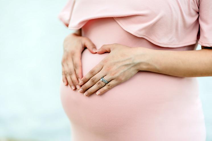 une femme enceinte fait un coeur sur son ventre 