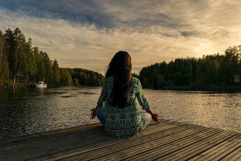 une femme qui fait du yoga devant un lac