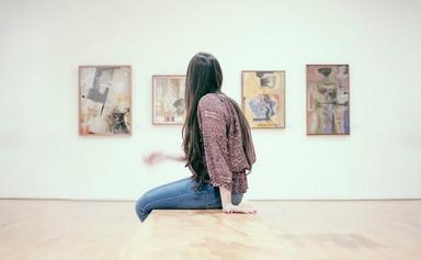 une fille assise observe les tableaux d'une exposition