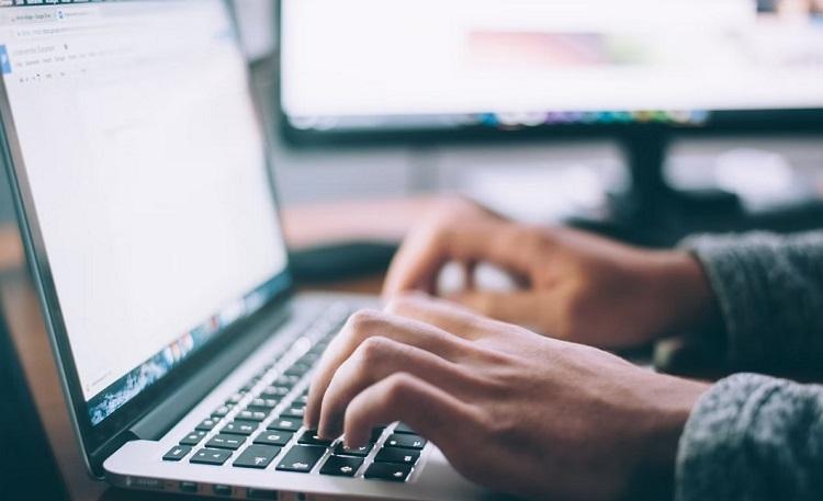 un homme écrit sur un clavier d'ordinateur portable