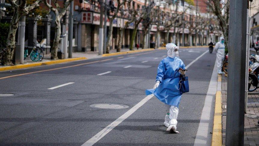 une femme marche dans la rue de Shanghai en combinaison contre le covid