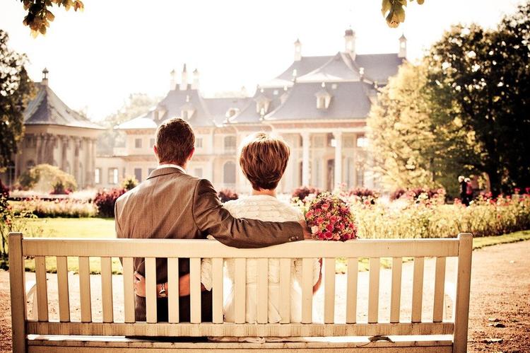 couple marié assis sur un banc devant une maison