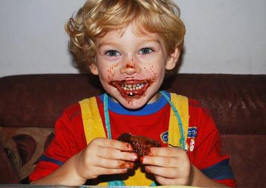 Petit garçon bouche pleine de chocolat