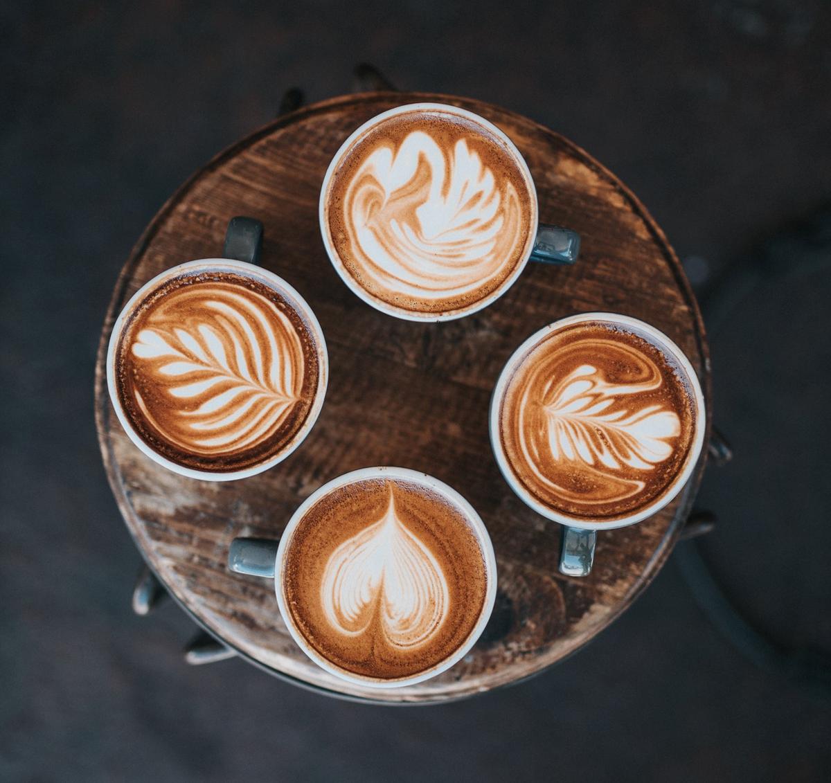 Quatre cafés latte sont posés sur une table 