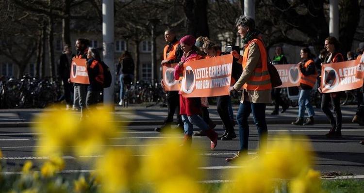 Militants de Letzte Generation défilant avec une banderole "Vor den Kipppunkten"