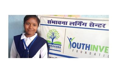 une jeune fille suivant le programme devant l'affiche de YouthInvest Foundation