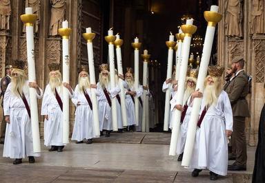 des hommes en blanc avec des cierges immenses lors de la procession du corpus christi à valencia