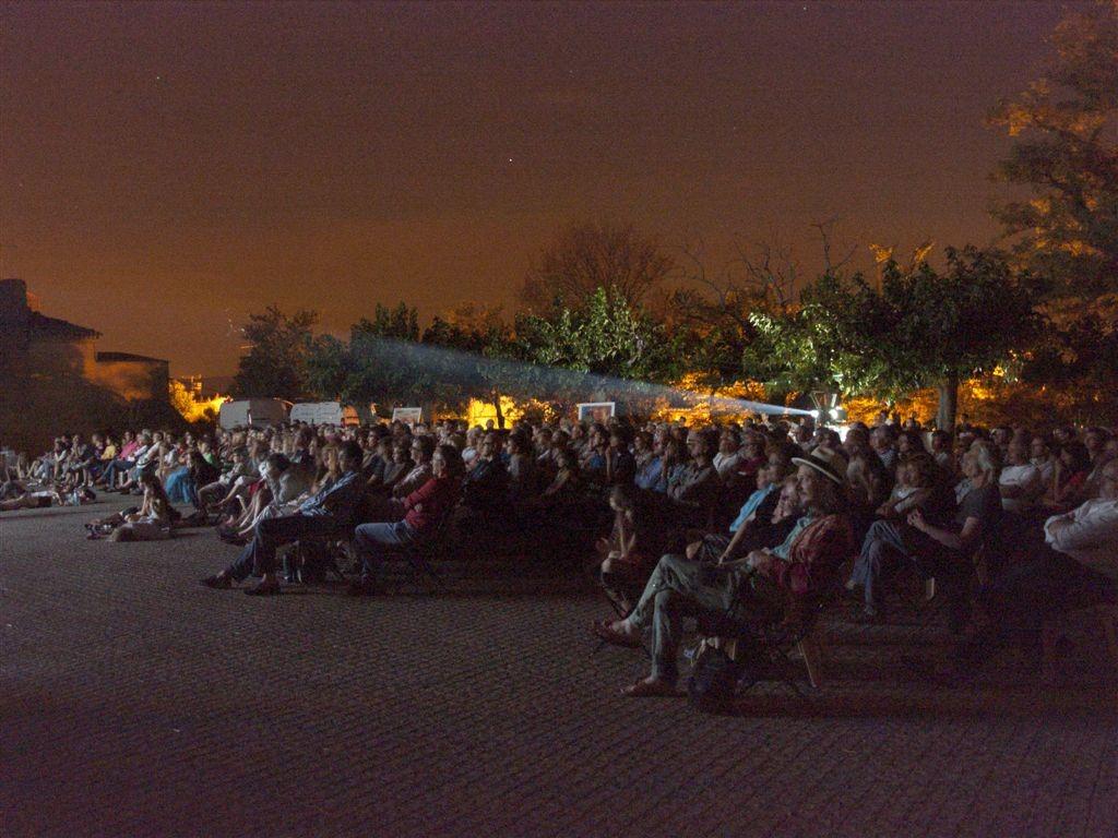 des personnes assises regardent un film en plein air de nuit