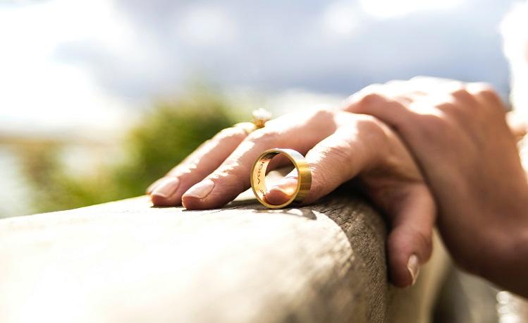 une main tient une alliance de mariage au bout du doigt -unsplash