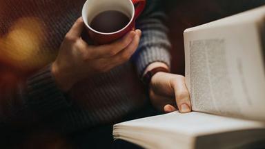 uen personne lisant un livre avec un café