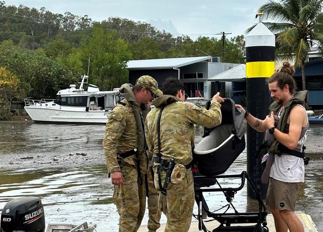 Deux militaires aident à évacuer des civils dans l'Etat de Queensland lors des inondations fin 2023