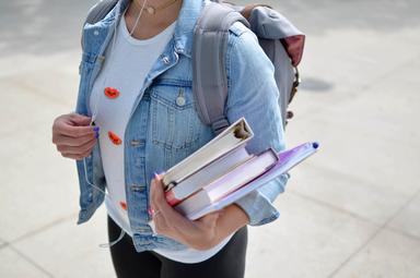 jeune étudiante erasmus portant une veste en jean bleue tenant un livre à Valencia