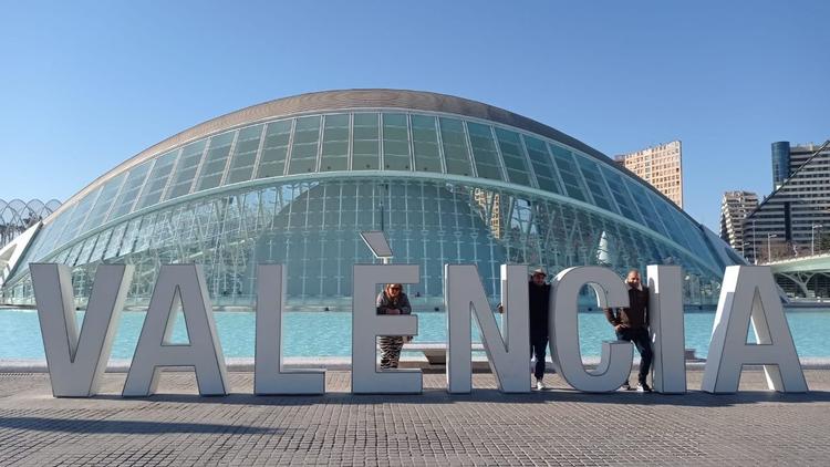 des touristes en train de se faire prendre en photo devant les lettres de valencia a la cuitat de les arts