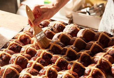 Un boulanger prepare une plaque de hot cross buns pour Paques