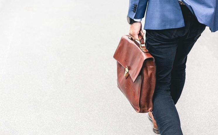 un homme marche au travail avec sacoche en cuir