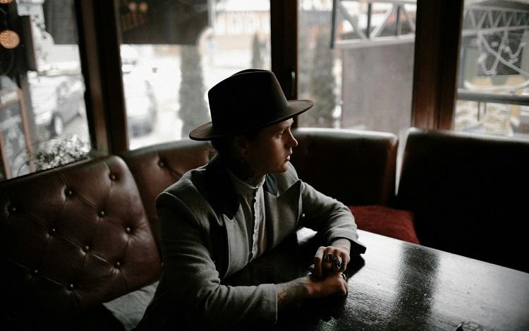 jeune homme assis avec chapeau borsalino sur la tête